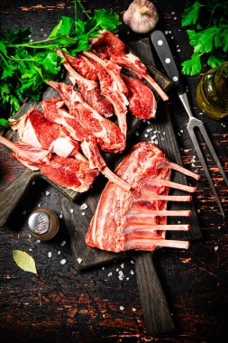 Raw rack of lamb with parsley on a cutting board. On a dark rustic background. High quality photo