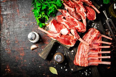 Raw rack of lamb with parsley on a cutting board. On a dark rustic background. High quality photo