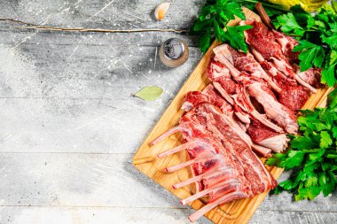 Raw rack of lamb on a wooden cutting board with parsley. On a gray background. High quality photo