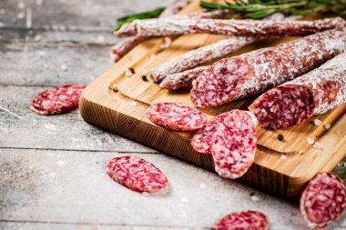 Pieces of salami sausage with sprigs of rosemary. On a gray background. High quality photo