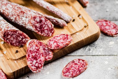 Pieces of salami sausage on a cutting board. On a rustic background. High quality photo