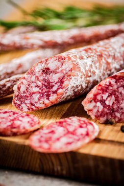 Pieces of salami sausage on a cutting board. On a rustic background. High quality photo