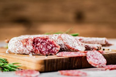 Pieces of salami sausage on a cutting board. On a rustic background. High quality photo