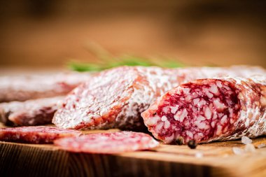 Pieces of salami sausage on a cutting board. On a rustic background. High quality photo