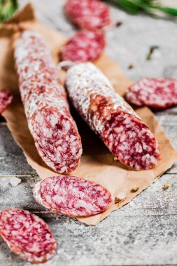 Pieces of salami sausage with sprigs of rosemary. On a gray background. High quality photo