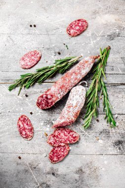 Pieces of salami sausage with sprigs of rosemary. On a gray background. High quality photo