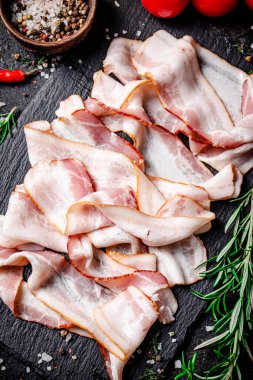 Domatesli ve biberiyeli taş bir tahtanın üzerinde pastırma parçaları. Siyah bir arka planda. Yüksek kalite fotoğraf