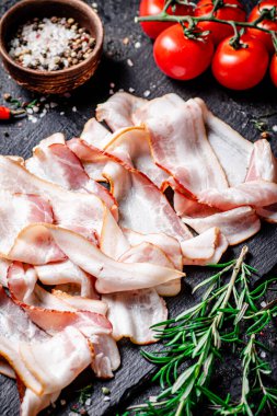 Domatesli ve biberiyeli taş bir tahtanın üzerinde pastırma parçaları. Siyah bir arka planda. Yüksek kalite fotoğraf