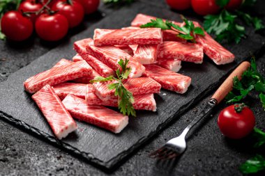 Taş tahtada taze domates ve bitkilerle yengeç eti. Siyah bir arka planda. Yüksek kalite fotoğraf