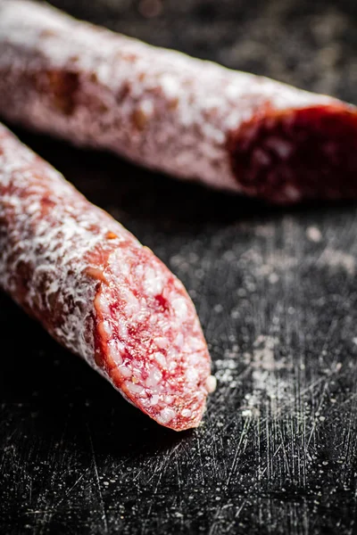 Sticks of salami sausage on the table. On a black background. High quality photo