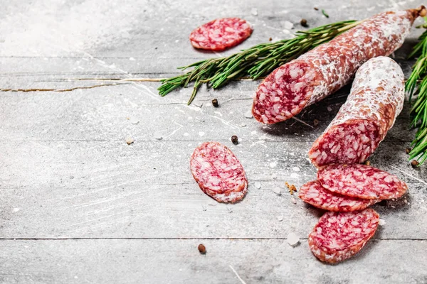 stock image Pieces of salami sausage with sprigs of rosemary. On a gray background. High quality photo