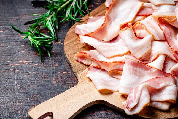 stock image Strips of bacon on a cutting board. Against a dark background. High quality photo