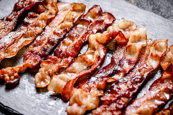 Strips of fried bacon on a black background. High quality photo