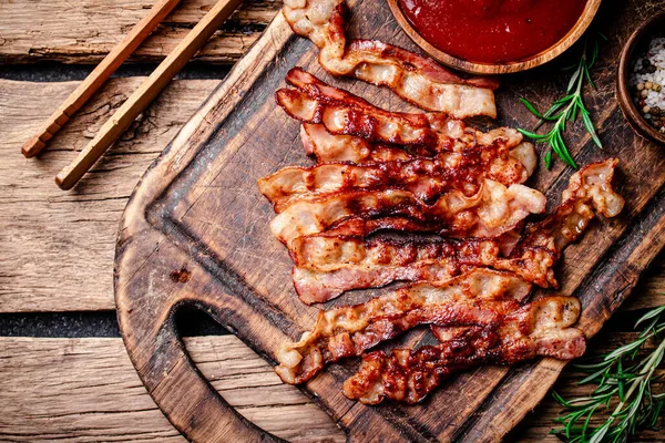 stock image Pieces of fried bacon with tomato sauce. On a wooden background. High quality photo