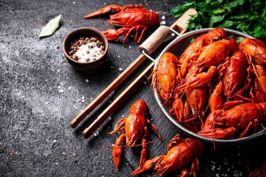 Taş bir tahtanın üzerinde kevgire batırılmış kerevit. Siyah bir arka planda. Yüksek kalite fotoğraf