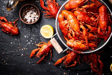 Taş bir tahtanın üzerinde kevgire batırılmış kerevit. Siyah bir arka planda. Yüksek kalite fotoğraf