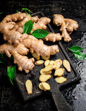 Kesme tahtasının üzerinde zencefil var. Siyah bir arka planda. Yüksek kalite fotoğraf