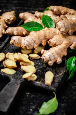 Kesme tahtasının üzerinde zencefil var. Siyah bir arka planda. Yüksek kalite fotoğraf