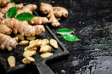 Kesme tahtasının üzerinde zencefil var. Siyah bir arka planda. Yüksek kalite fotoğraf