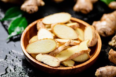 Tahta tabakta taze zencefil kökü parçaları. Siyah bir arka planda. Yüksek kalite fotoğraf