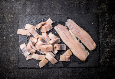 Taş bir tahtanın üzerinde lezzetli tuzlanmış ringa balıkları. Siyah bir arka planda. Yüksek kalite fotoğraf