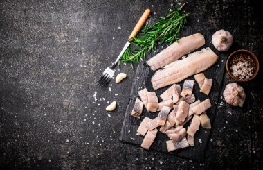 Sarımsak ve biberiyeli taş bir tahtanın üzerinde tuzlanmış ringa balıkları. Siyah bir arka planda. Yüksek kalite fotoğraf