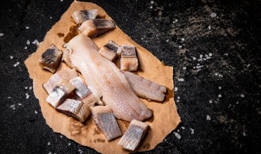 Kağıt üzerinde tuzlanmış ringa balığı parçaları. Siyah bir arka planda. Yüksek kalite fotoğraf