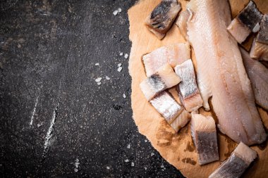 Kağıt üzerinde tuzlanmış ringa balığı parçaları. Siyah bir arka planda. Yüksek kalite fotoğraf
