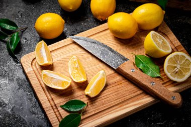 Tahta kesme tahtasında bıçakla taze limon dilimlenmiş. Siyah bir arka planda. Yüksek kalite fotoğraf