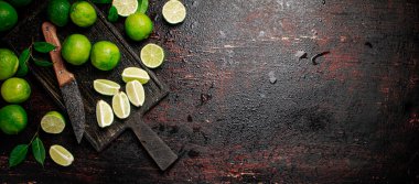 Kesme tahtasındaki yapraklarla dilimlenmiş kireç ve bıçak. Kırsal bir arka planda. Yüksek kalite fotoğraf