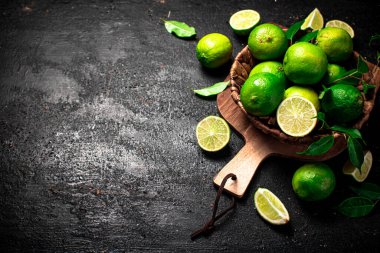 Kesme tahtasındaki sepetin içinde olgunlaşmış kireç. Siyah bir arka planda. Yüksek kalite fotoğraf