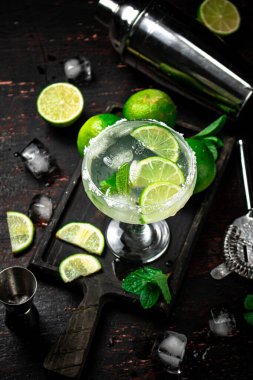 Limon ve nane yapraklarıyla kesilmiş bir panoda margarita. Kırsal bir arka planda. Yüksek kalite fotoğraf