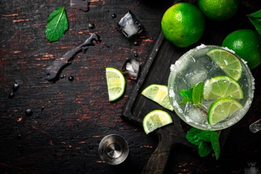 Limon ve nane yapraklarıyla kesilmiş bir panoda margarita. Kırsal bir arka planda. Yüksek kalite fotoğraf