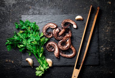 Taze ahtapot parçaları yeşil taşlı bir tahtanın üzerinde. Siyah bir arka planda. Yüksek kalite fotoğraf