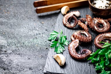 Taze ahtapot parçaları yeşil taşlı bir tahtanın üzerinde. Siyah bir arka planda. Yüksek kalite fotoğraf