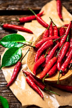 Tabağında yapraklar olan acı kırmızı biber. Ahşap bir arka planda. Yüksek kalite fotoğraf