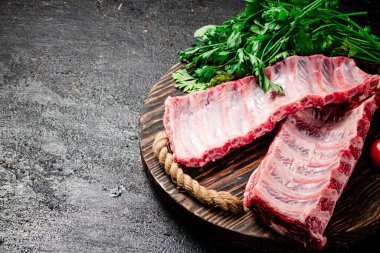 Tahta tepside çiğ pirzola ve yeşillik. Siyah bir arka planda. Yüksek kalite fotoğraf