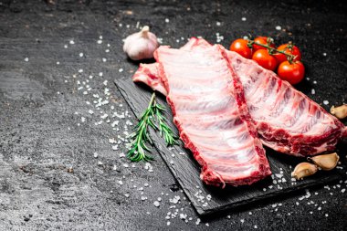 Domatesli ve tuzlu taş bir tahtada çiğ pirzola. Siyah bir arka planda. Yüksek kalite fotoğraf