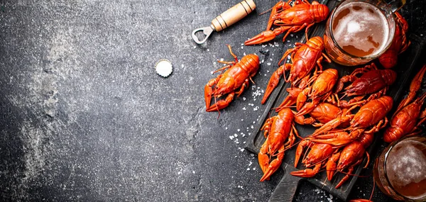 stock image Boiled crayfish with beer on a cutting board. On a black background. High quality photo