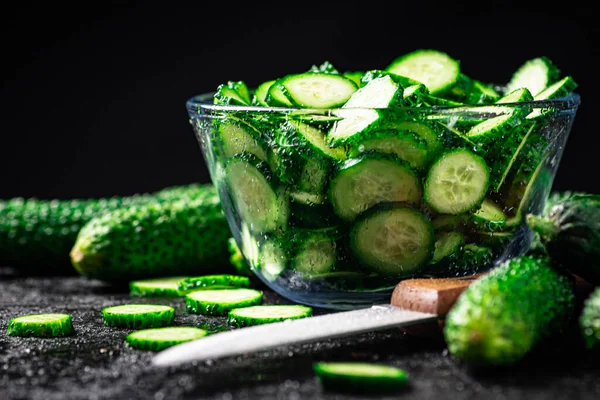 Full glass bowl of chopped fresh cucumbers. On a black background. High quality photo