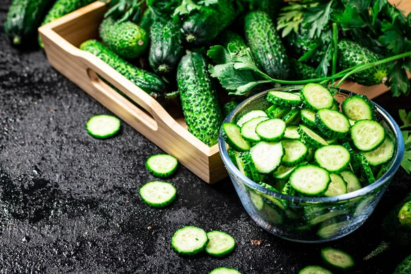 Full glass bowl of chopped fresh cucumbers. On a black background. High quality photo