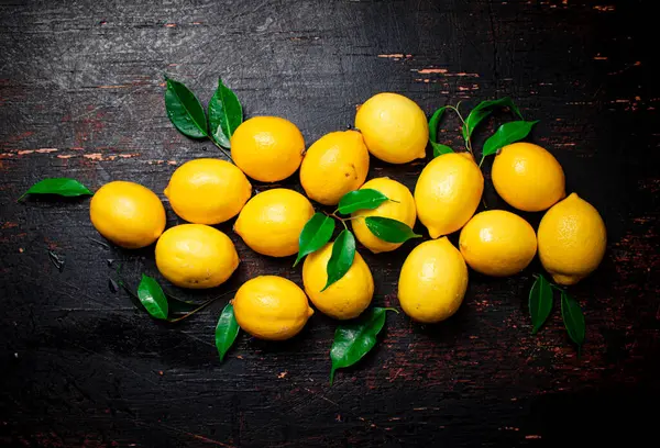 Stock image Juicy lemons with foliage on the table. On a rustic dark background. High quality photo