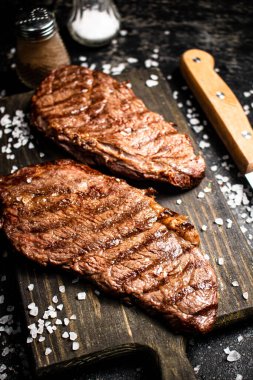 Ahşap kesme tahtasında ızgara biftek. Siyah bir arka planda. Yüksek kalite fotoğraf
