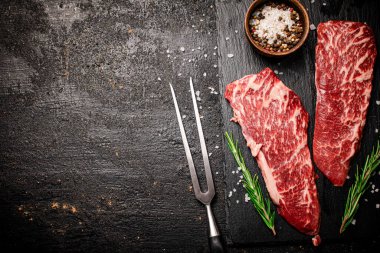 Taş bir tahtanın üzerinde çiğ biftek. Siyah bir arka planda. Yüksek kalite fotoğraf