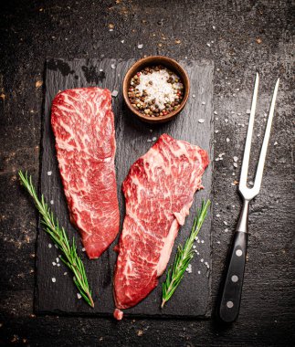 Taş bir tahtanın üzerinde çiğ biftek. Siyah bir arka planda. Yüksek kalite fotoğraf