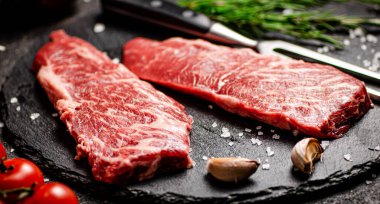 Taş bir tahtanın üzerinde çiğ biftek. Siyah bir arka planda. Yüksek kalite fotoğraf