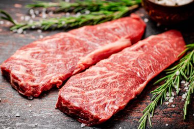 Biberiyeli çiğ biftek ve masada baharatlar. Karanlık bir arka plana karşı. Yüksek kalite fotoğraf