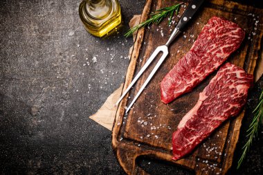 Kesme tahtasında çiğ biftek. Siyah bir arka planda. Yüksek kalite fotoğraf