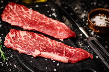 Kesme tahtasında çiğ biftek. Siyah bir arka planda. Yüksek kalite fotoğraf