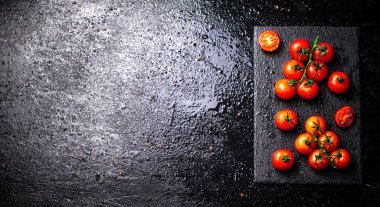 Taş bir tahtanın dalındaki taze domatesler. Siyah bir arka planda. Yüksek kalite fotoğraf